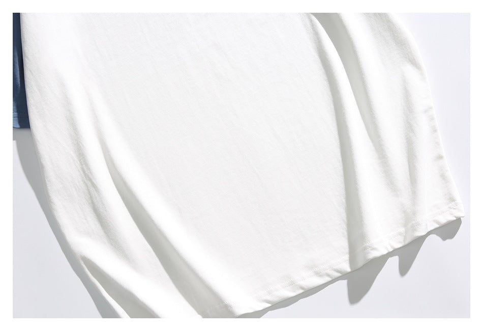 Close-up of the plain white T-shirt body and stitched bottom hem, with a glimpse of a blue sleeve.