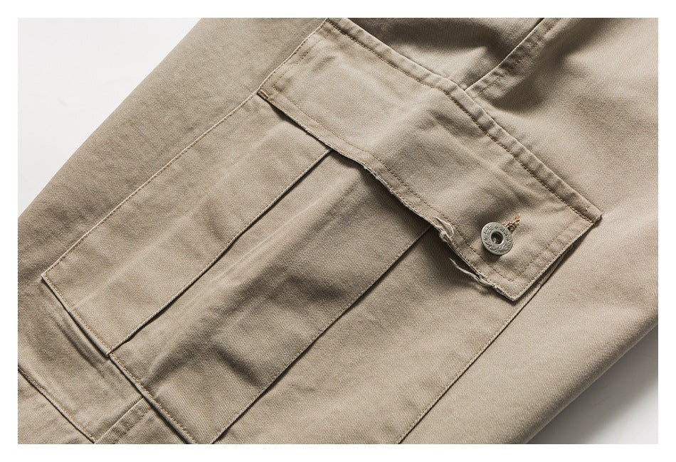 Close-up of a beige trouser cargo pocket with a buttoned flap and layered stitching.