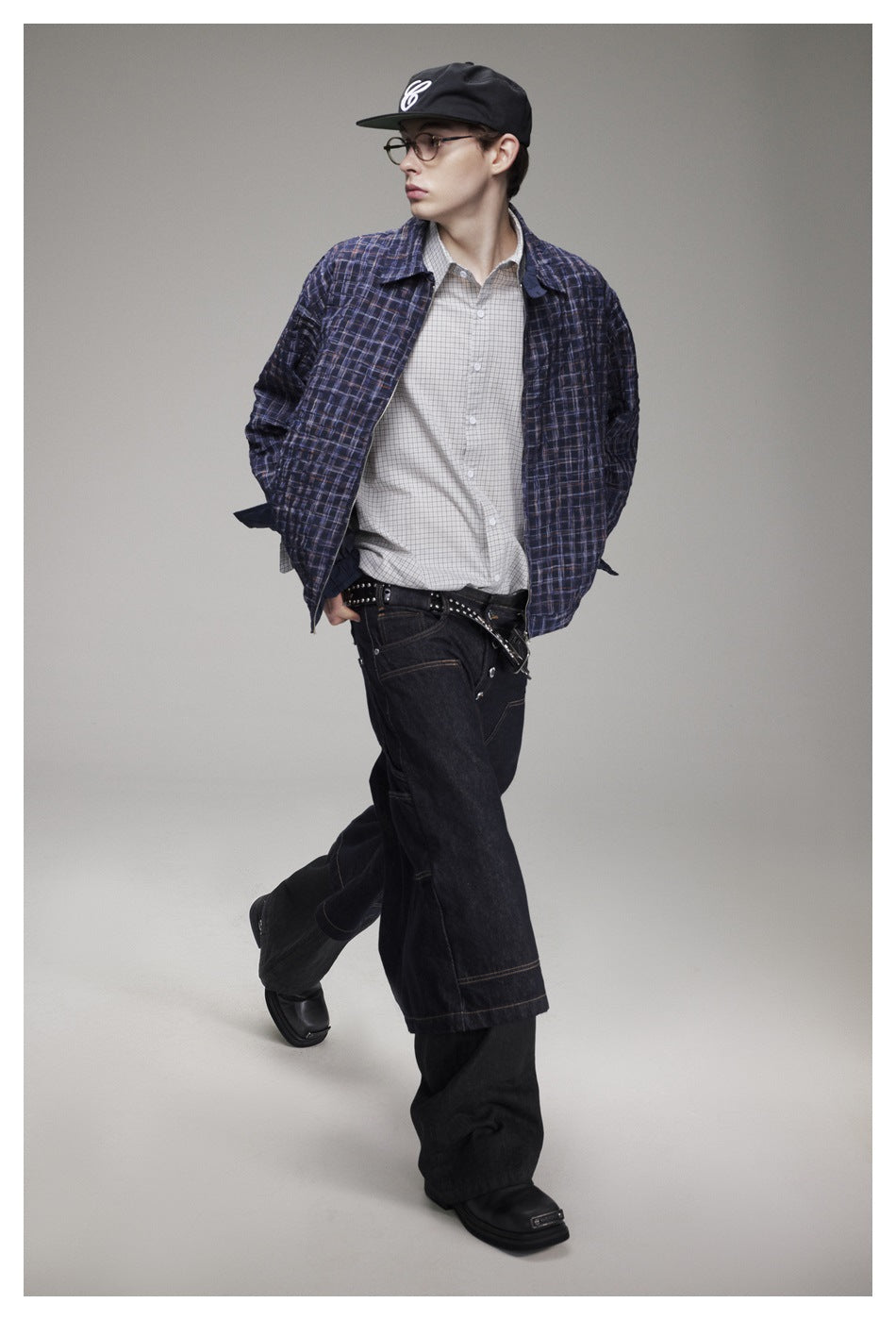 Model in a navy plaid jacket and light checked shirt, shown in a walking pose from the side.