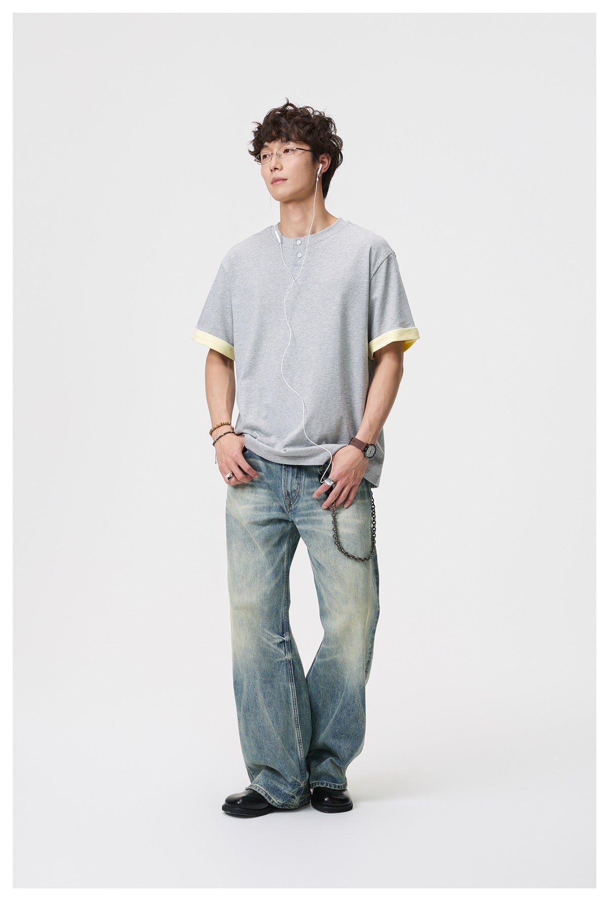 Full-length view of a model wearing a light gray Henley shirt with pale yellow rolled cuffs.
