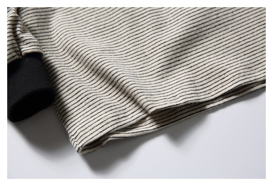 Close-up of a cream-and-black striped garment hem beside a solid black ribbed cuff.