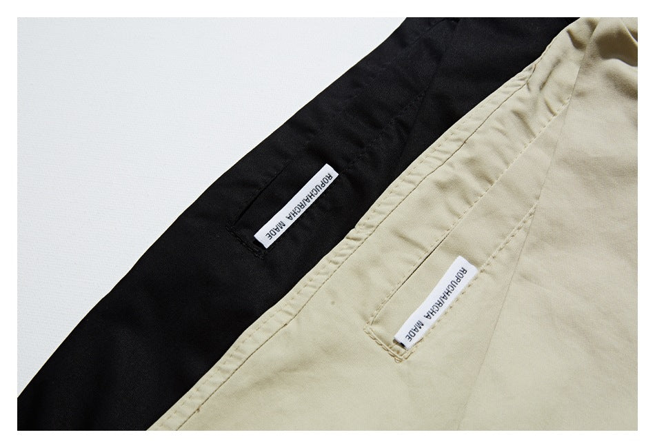 Close-up of beige and black garment seams with small sewn white labels bearing lettering.