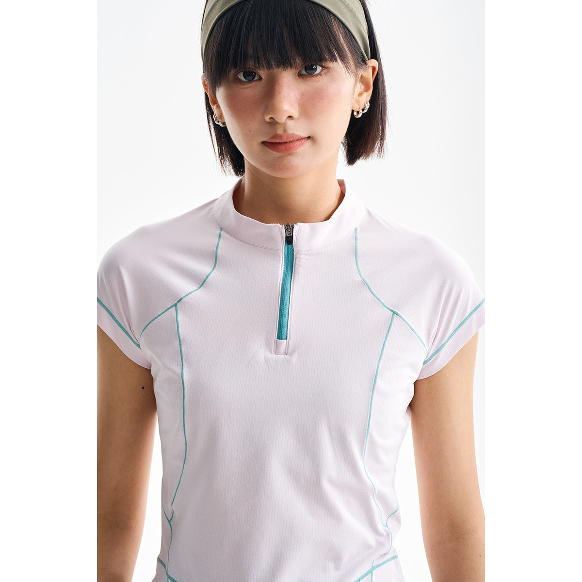 Close view of a model wearing a white short-sleeve quarter-zip top with turquoise zipper trim and curved seam detailing.