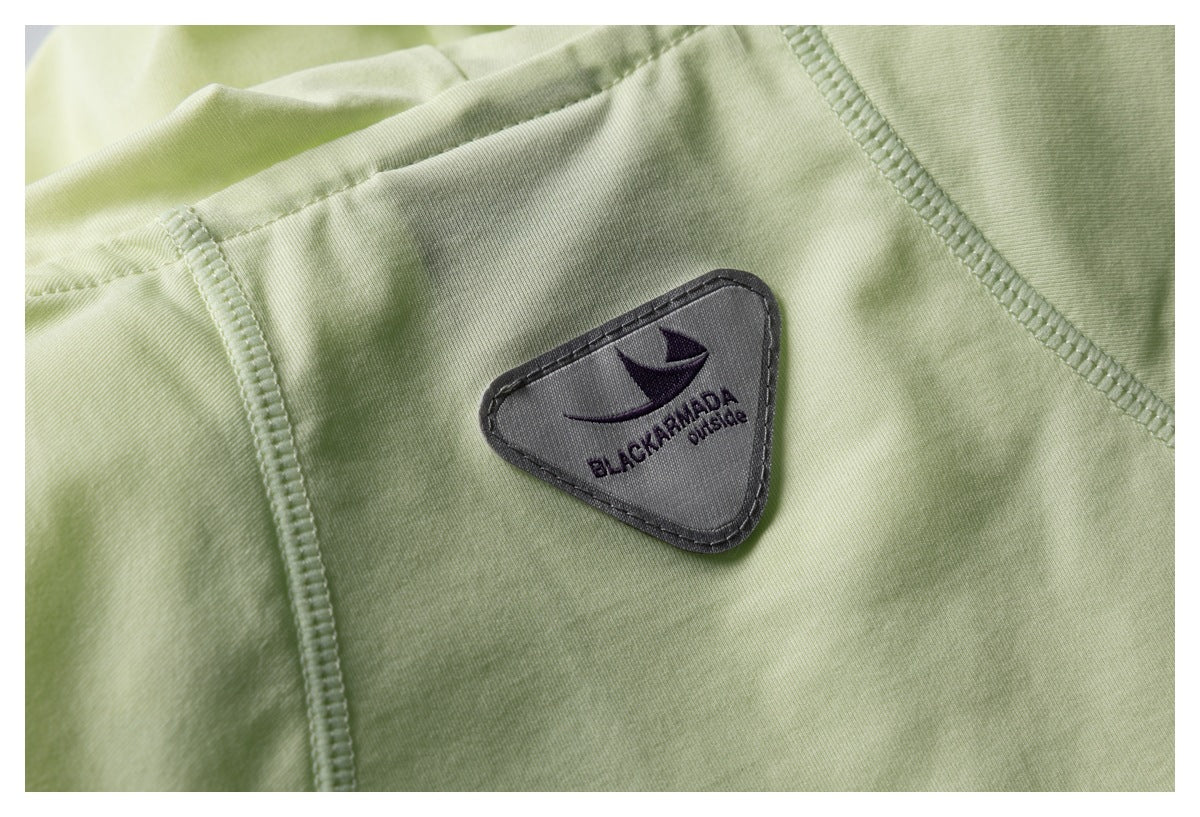 Close-up of a gray triangular brand patch on pale green fabric.