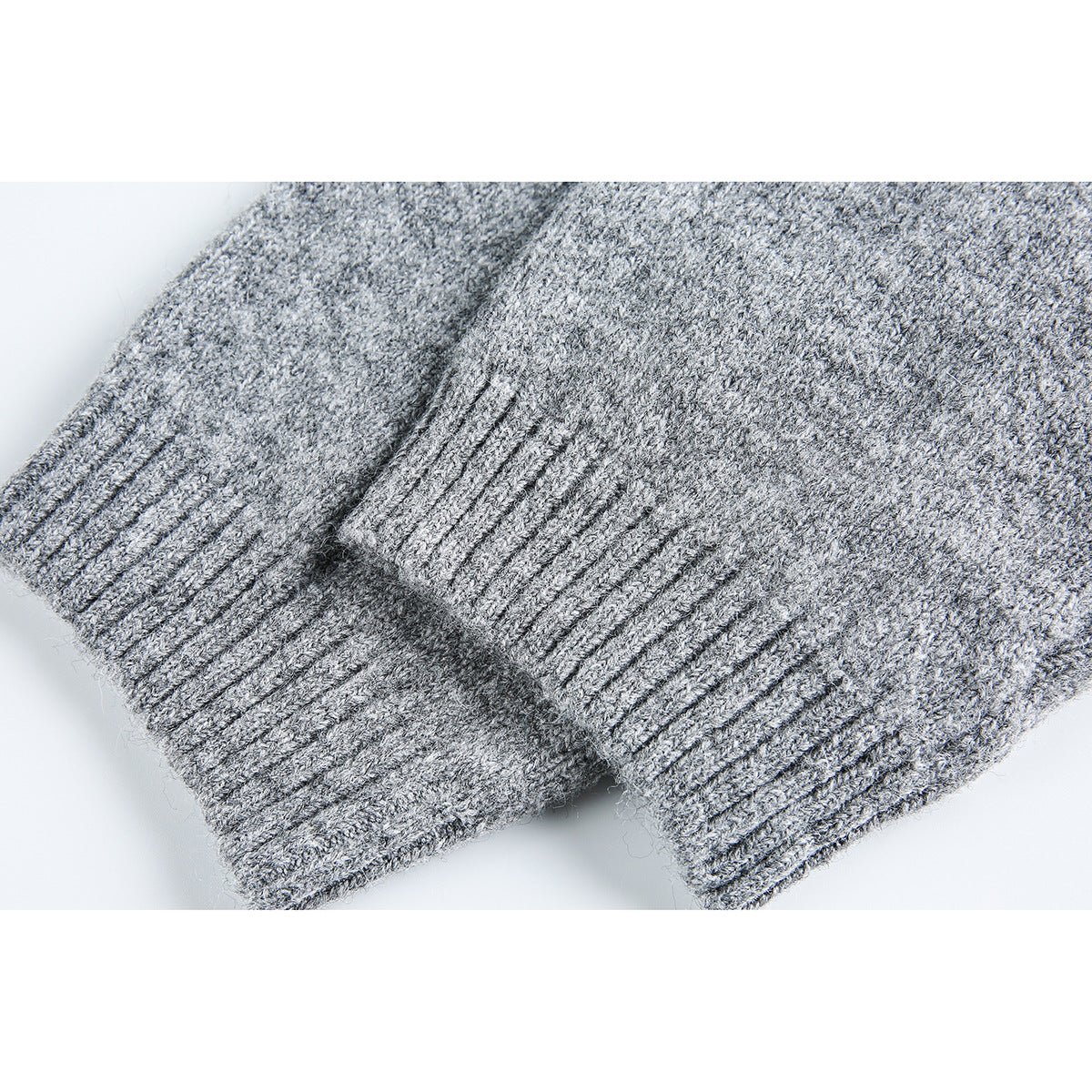 Close-up of gray knit sweater fabric and overlapping ribbed cuffs.