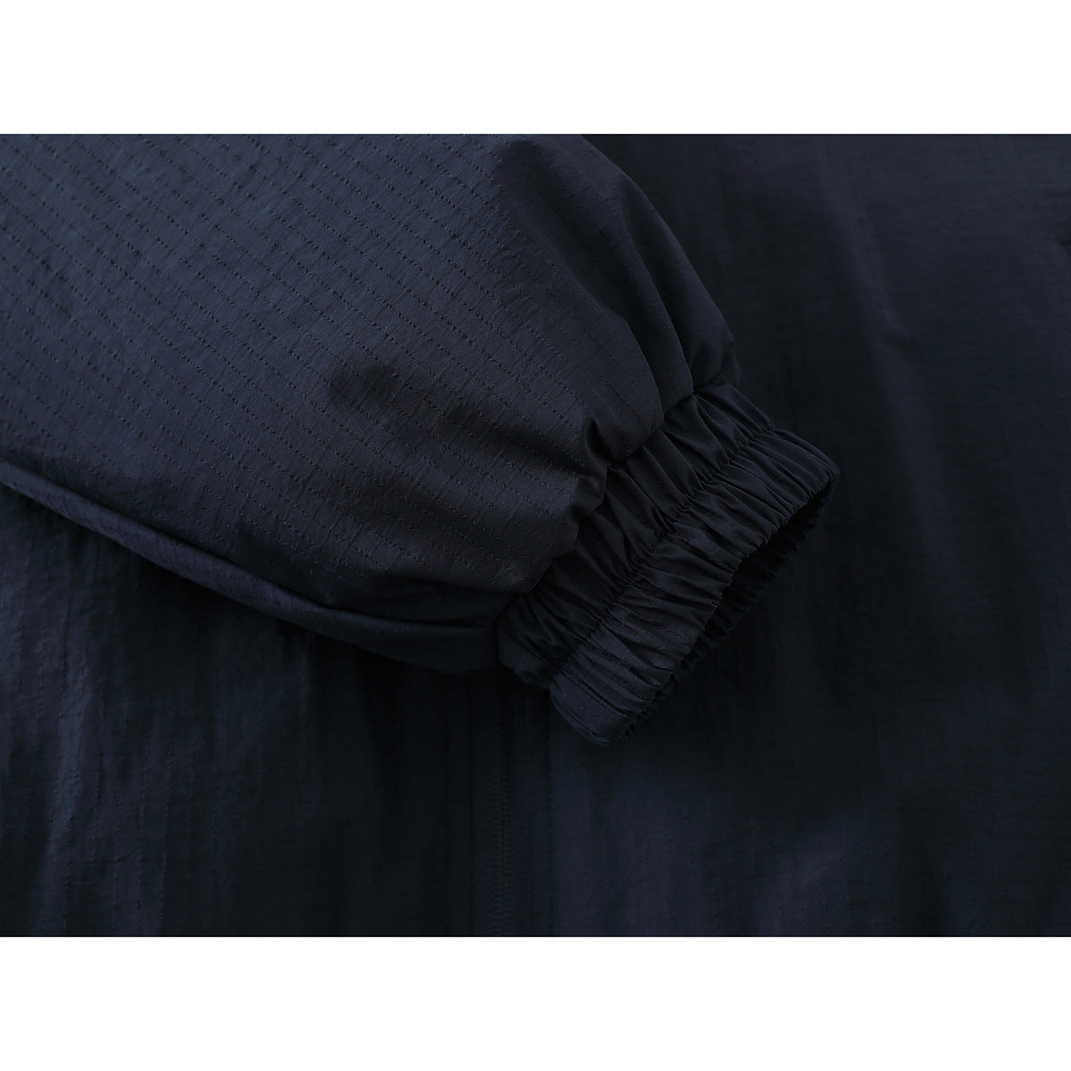 Close-up of a dark navy jacket sleeve ending in an elasticized cuff.