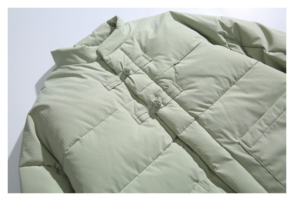 Close view of the pale sage jacket front, showing padded sections and fabric knot closures.