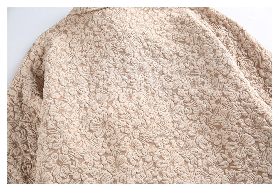 Close-up of beige fabric covered in raised floral embroidery.