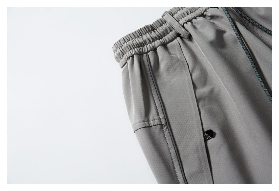 Close-up of gray pants showing the elastic waistband, side pocket seam, and small black toggle.