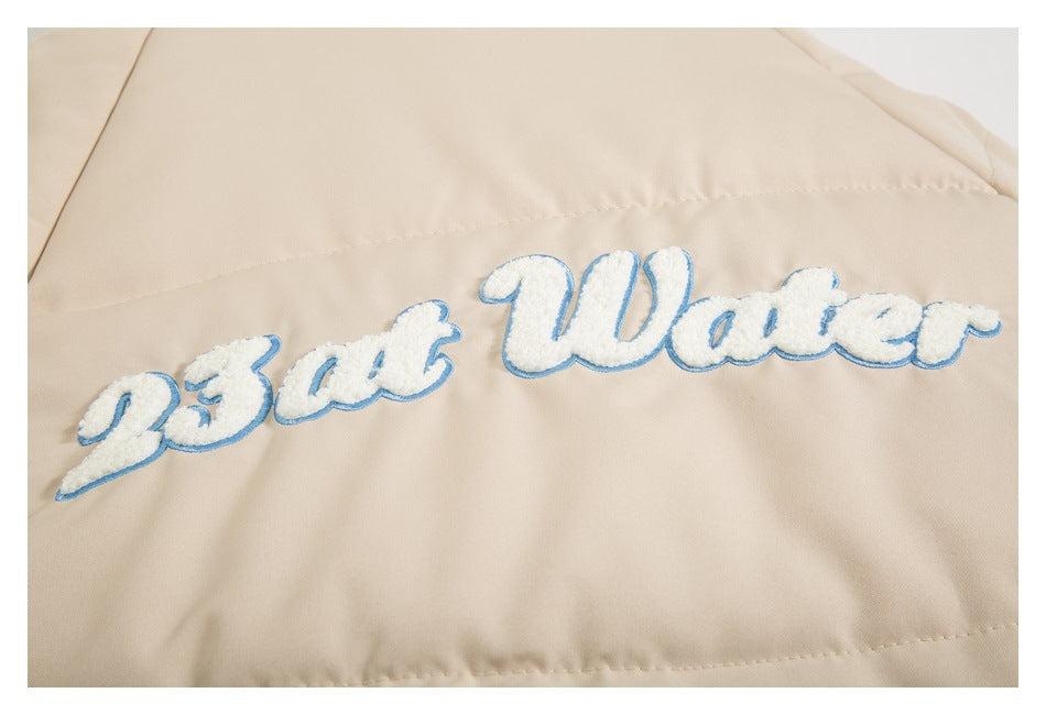 Close-up of white embroidered script with a blue outline on beige jacket fabric.