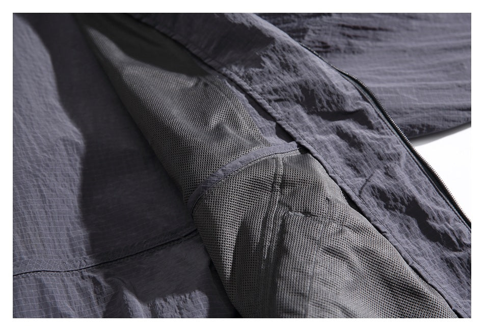 Close-up of a dark charcoal jacket showing mesh lining, stitched seams and a zipper.