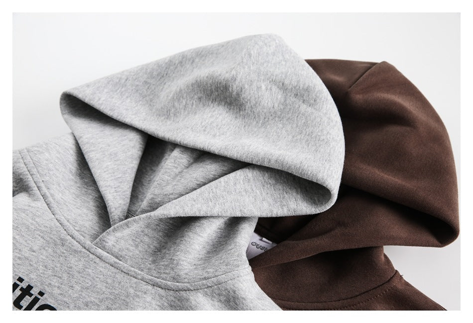 Close-up of the overlapping hoods and neckline areas of light gray and dark brown sweatshirts.