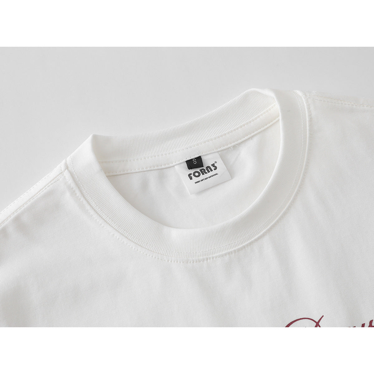 Close-up of a white T-shirt’s ribbed crew neck and inner neck label.