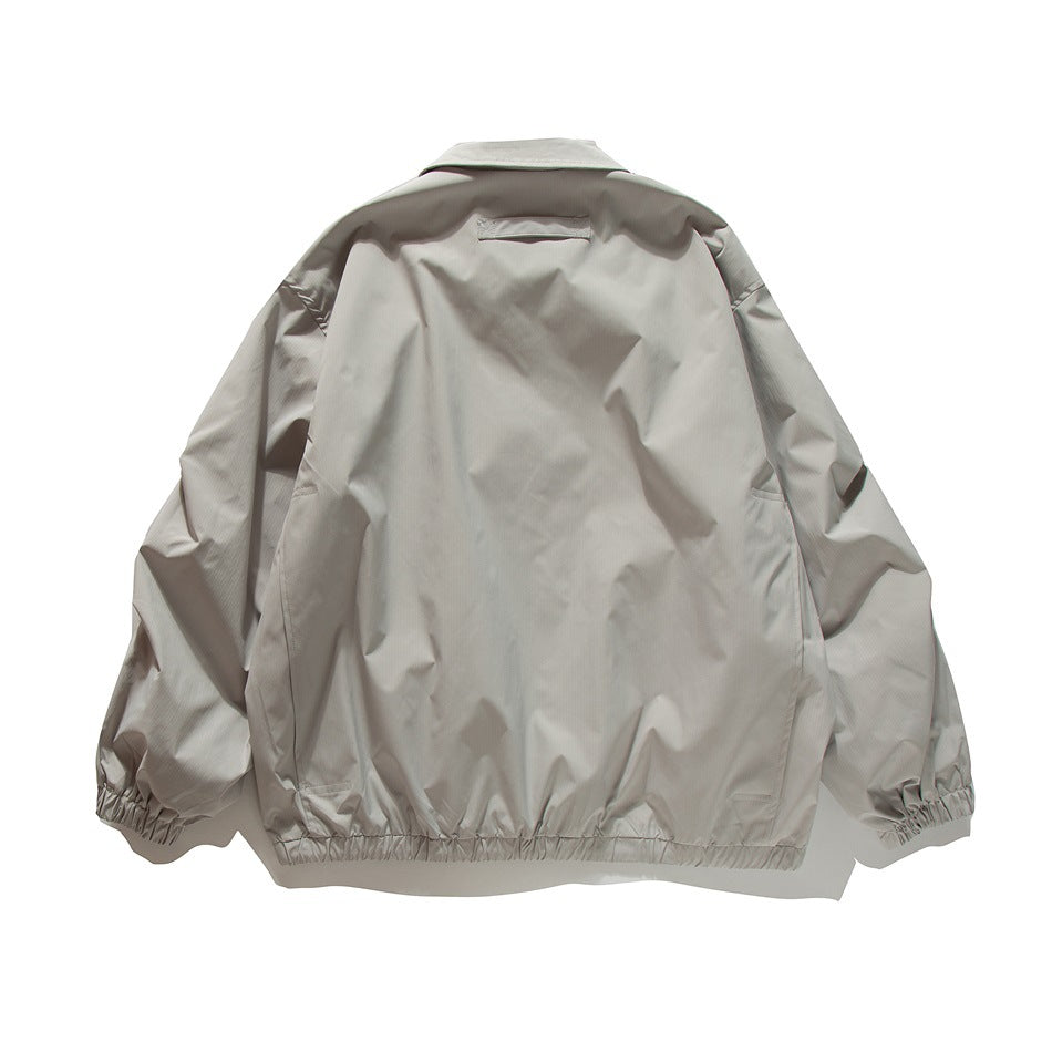 Back view of a light taupe jacket laid flat, with a collar, elastic cuffs, and a gathered hem.