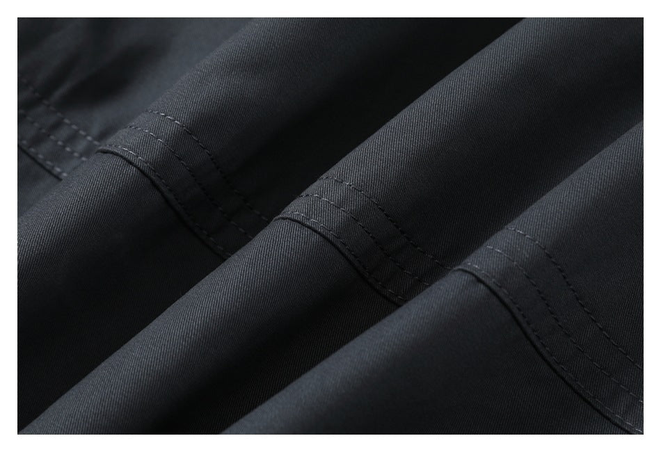 Close-up of dark charcoal fabric with parallel stitched seams and a fine diagonal weave.