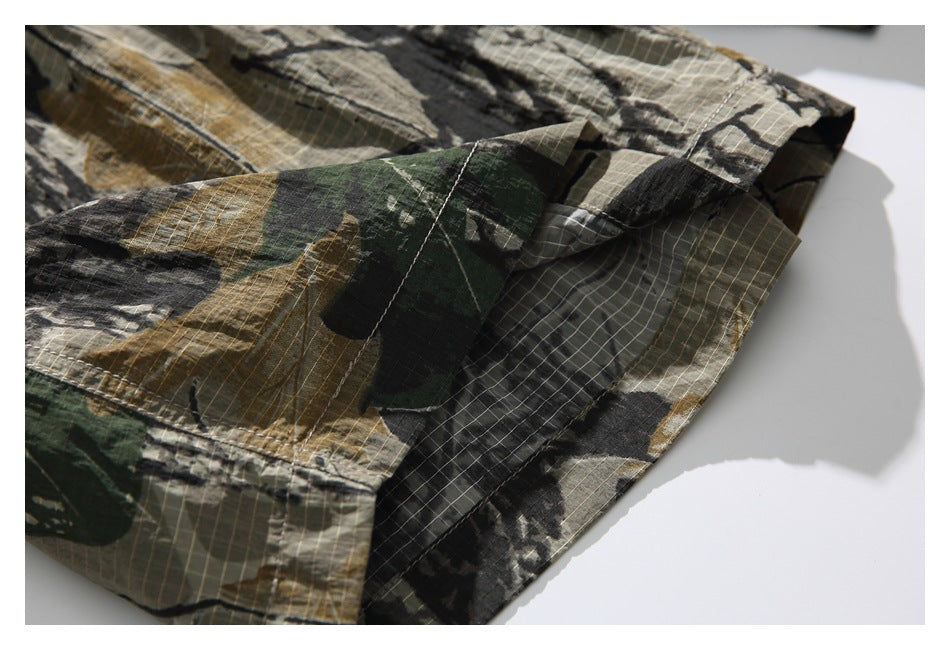Close-up of the camouflage shorts' stitched hem and overlapping fabric panels.