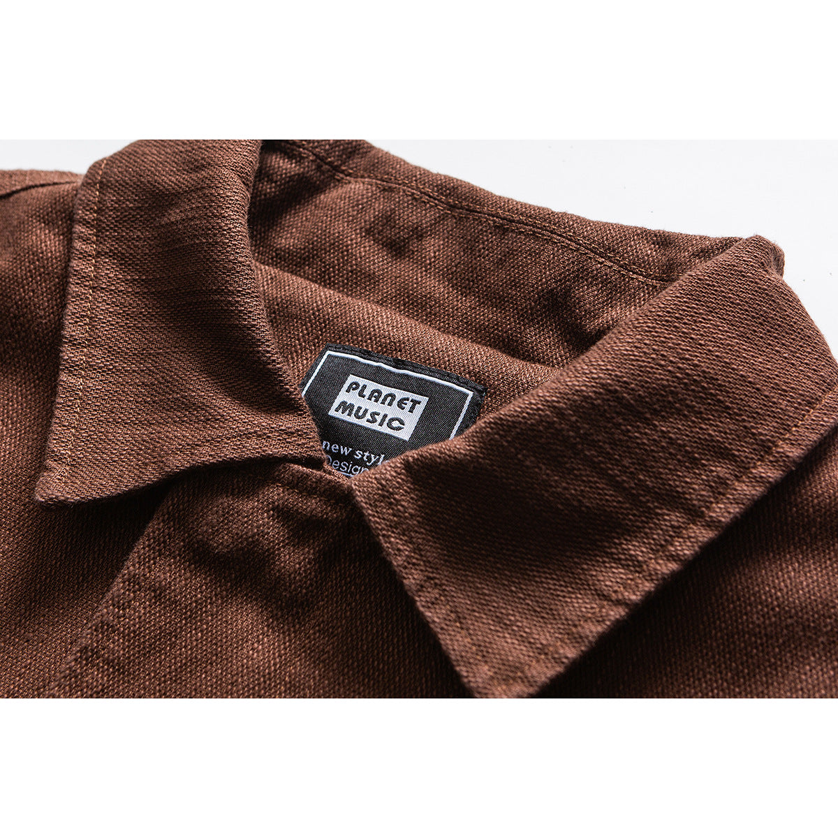 Close-up of a rust-brown jacket collar and textured fabric, with a sewn-in PLANET MUSIC label.