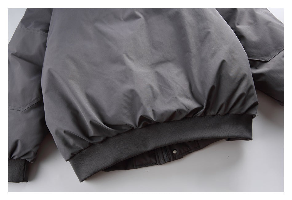 Close-up of a dark gray jacket’s gathered lower hem and wide ribbed waistband.