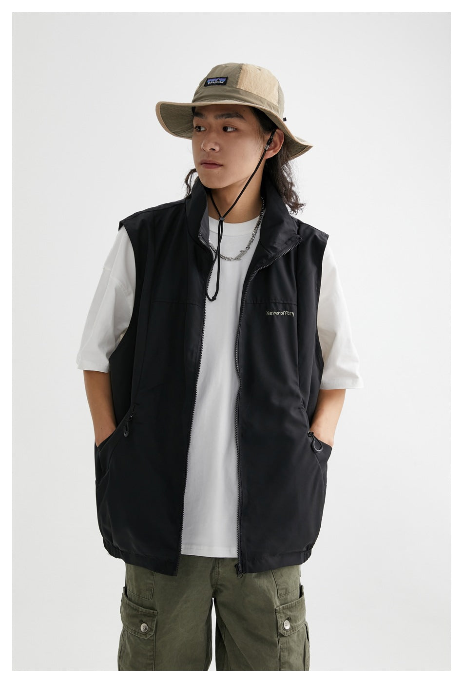 Model wearing the black stand-collar vest open over a white tee, hands in pockets, close-up view
