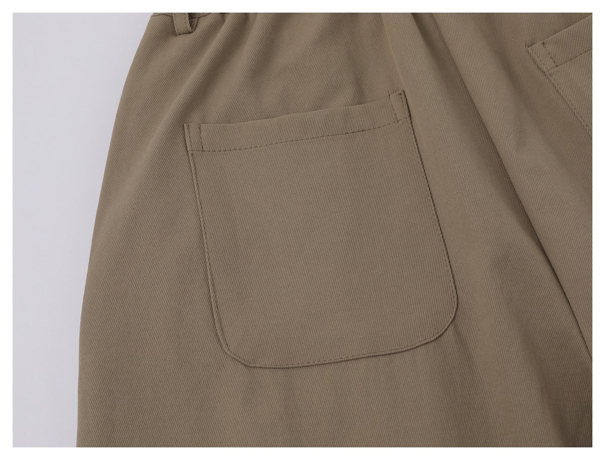 Close-up of a large stitched patch pocket on taupe trousers.