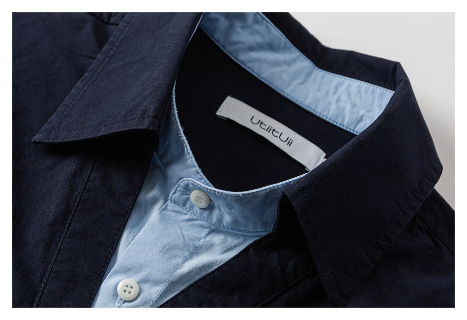Close-up of a dark navy shirt collar with pale blue inner placket, white buttons, and a sewn neck label.