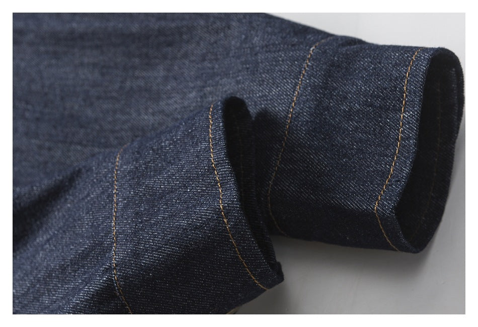 Close-up of a folded dark indigo denim cuff with tan stitching.