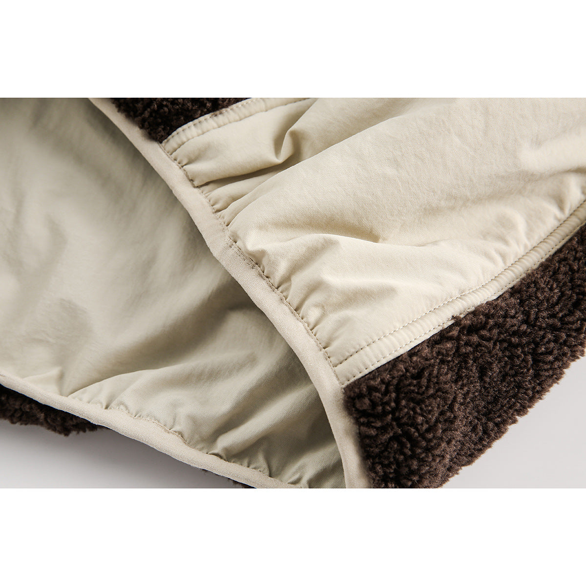 Close-up of the cream lining and stitched panel beside dark brown sherpa fabric.