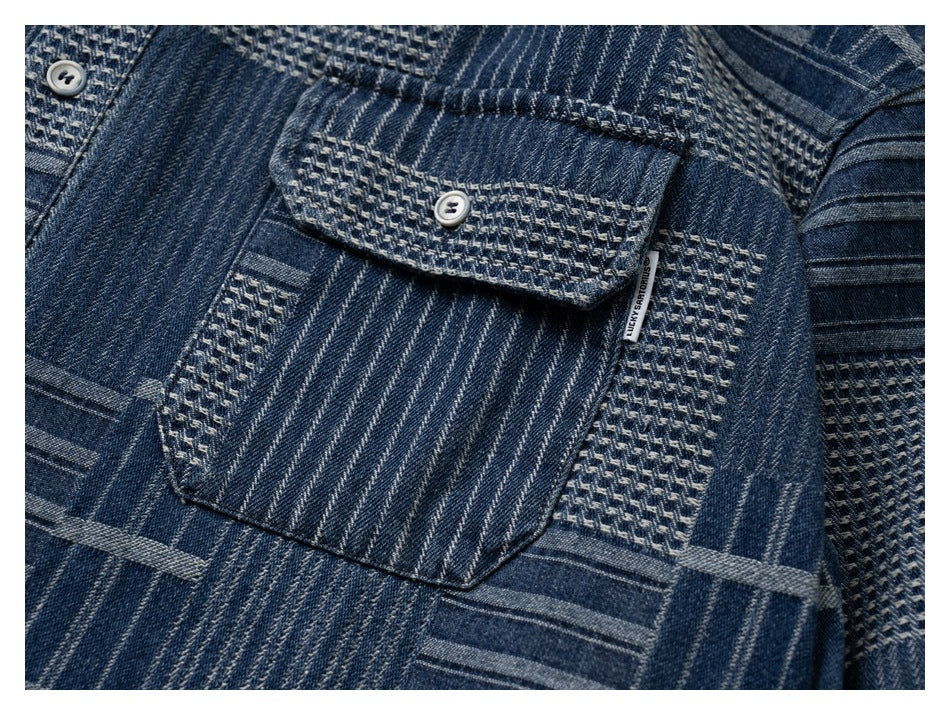 Close-up of a blue patterned shirt’s buttoned chest pocket and contrasting textured panels.
