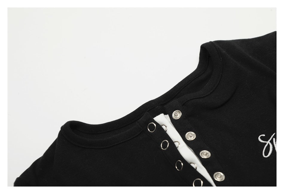 Close-up of the black top's round neckline and open snap-button placket with white fabric beneath.