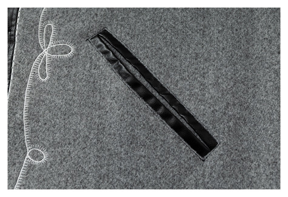 Close-up of a diagonal black-trimmed pocket on a gray jacket panel beside white loop embroidery.