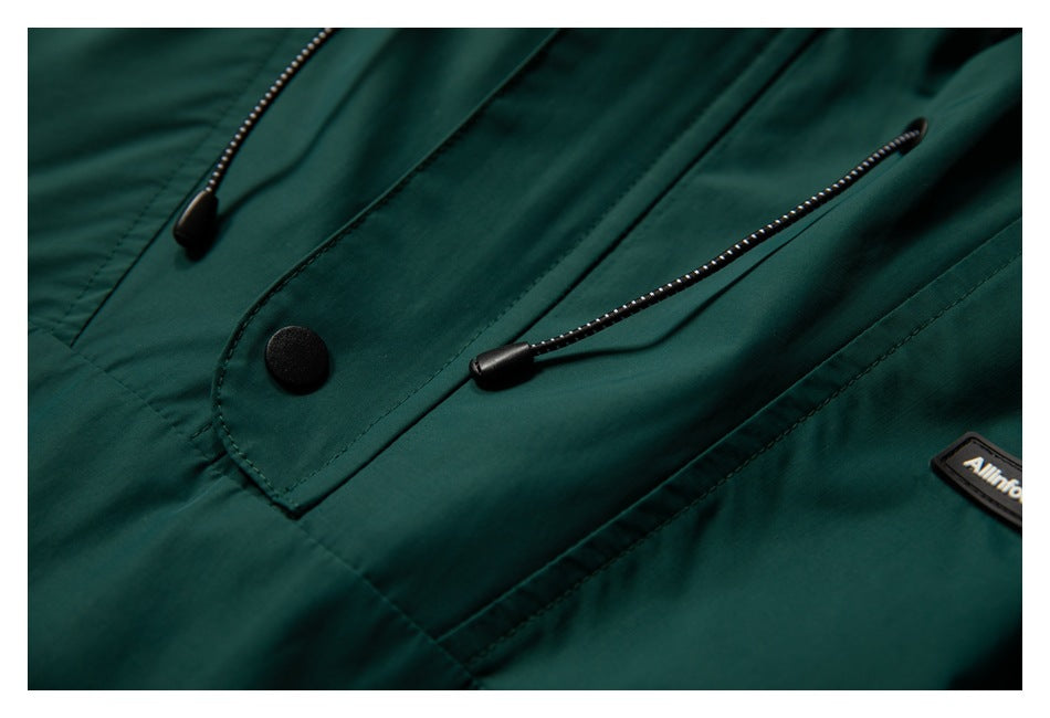 Close-up of the dark teal jacket's front placket with a black snap and adjustable drawcords.