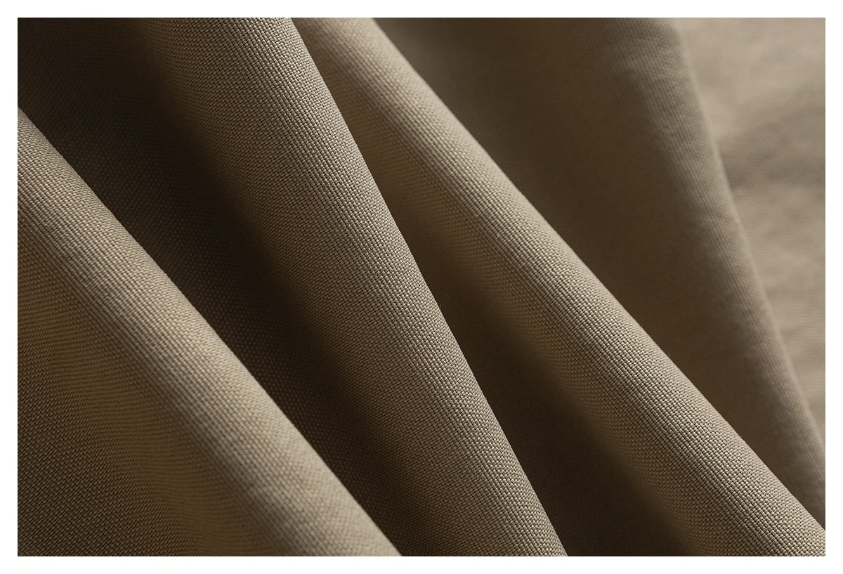 Macro view of the fine woven texture of tan trouser fabric.