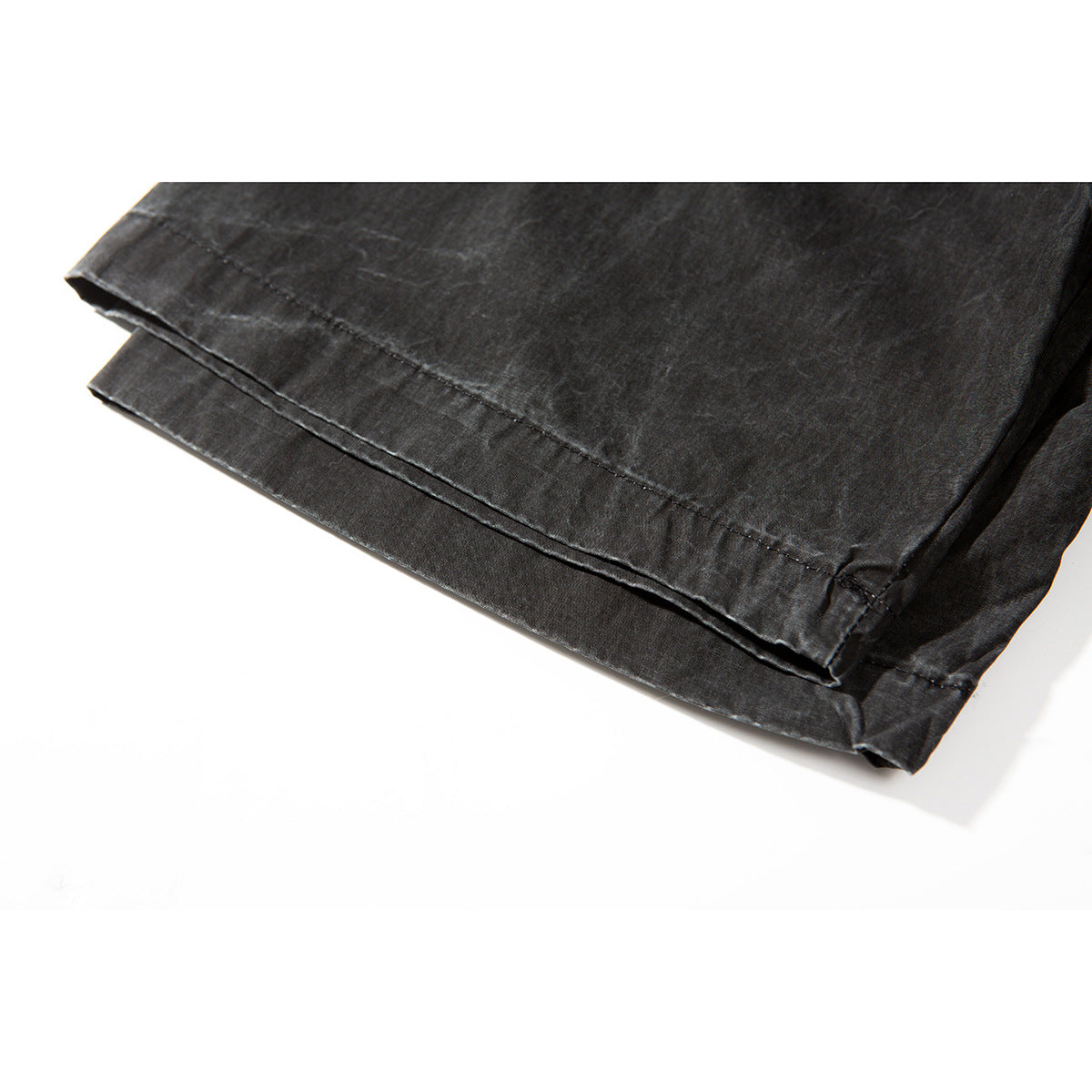 Close-up of the charcoal shirt’s curved bottom hem and double-row stitching.