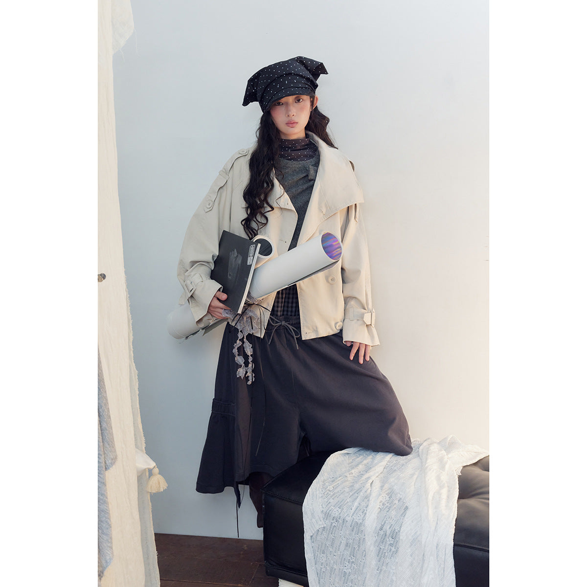 Model wearing a cream cropped jacket with wide lapels and button details, paired with dark bottoms and a polka-dot hat.