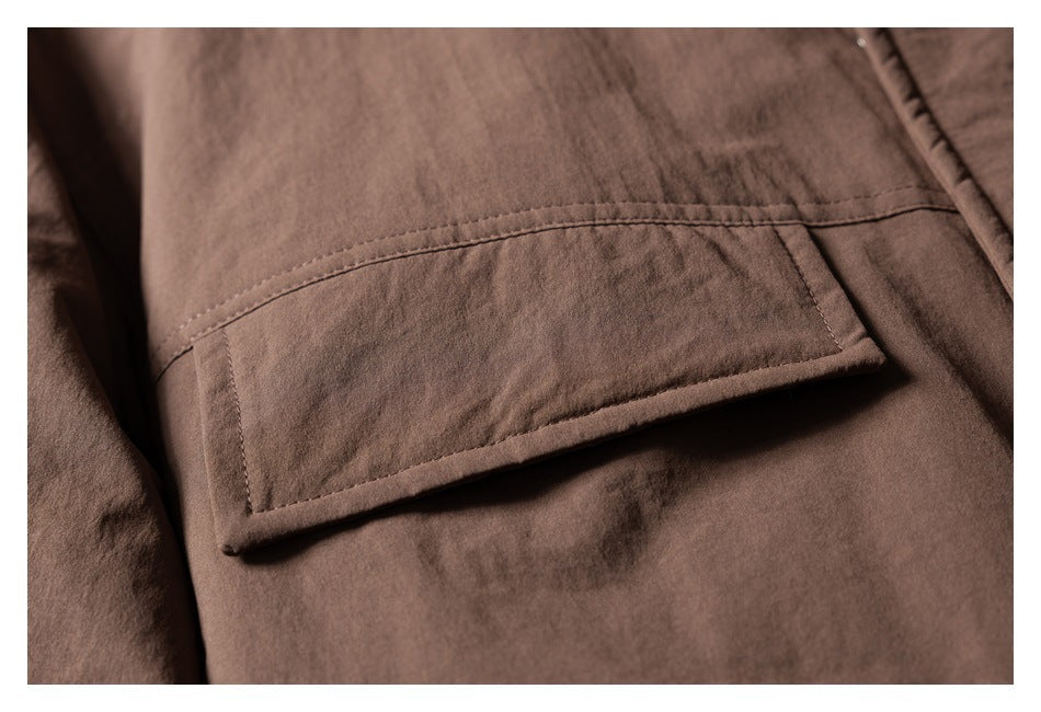 Close-up of a rectangular flap pocket on brown jacket fabric.