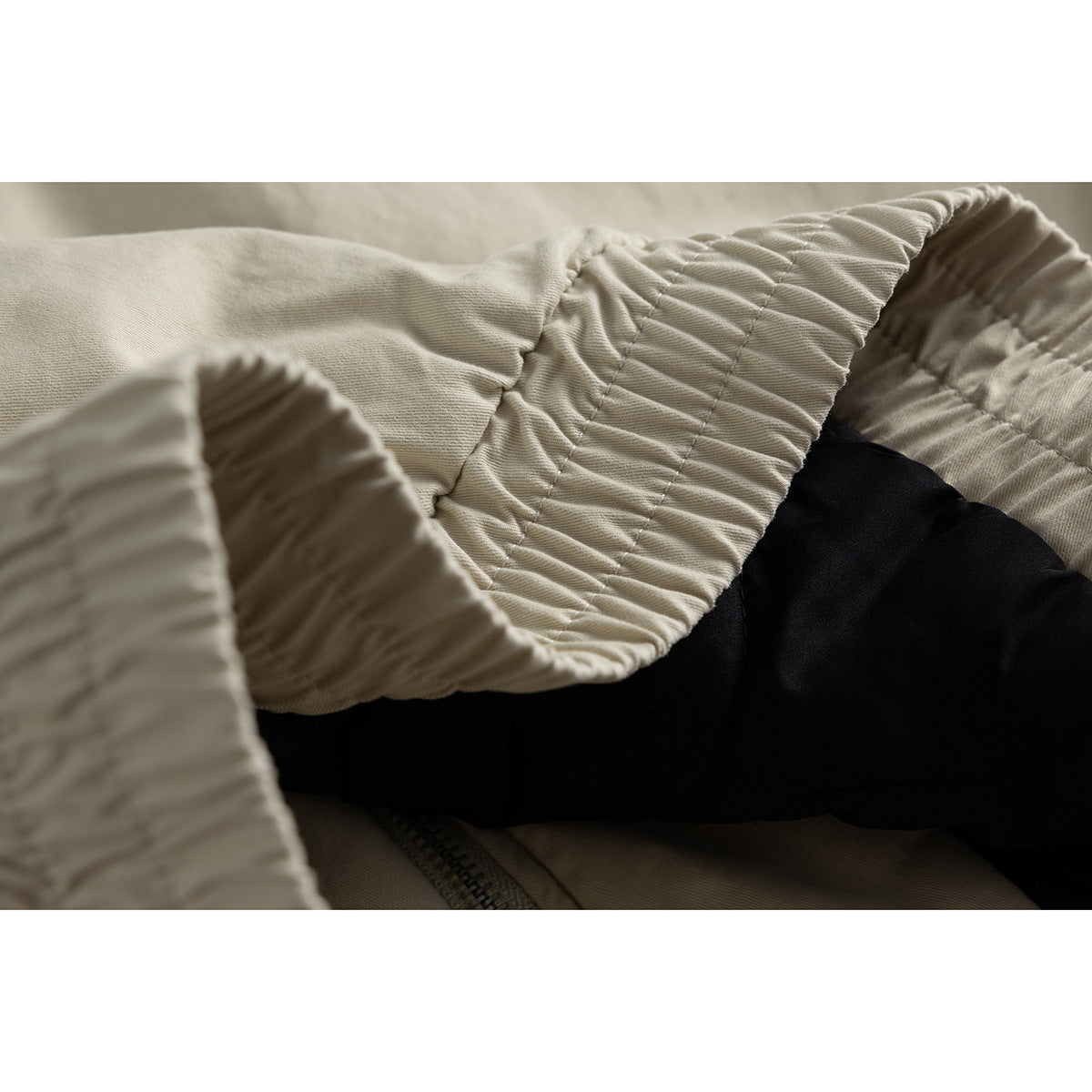 Close-up of the gathered beige jacket sleeve and cuff, with black lining visible inside.