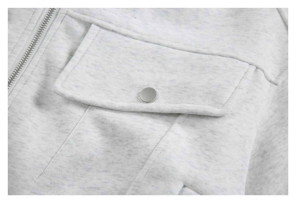 Close-up of a flap pocket with a round metal snap on the light gray marled jacket.