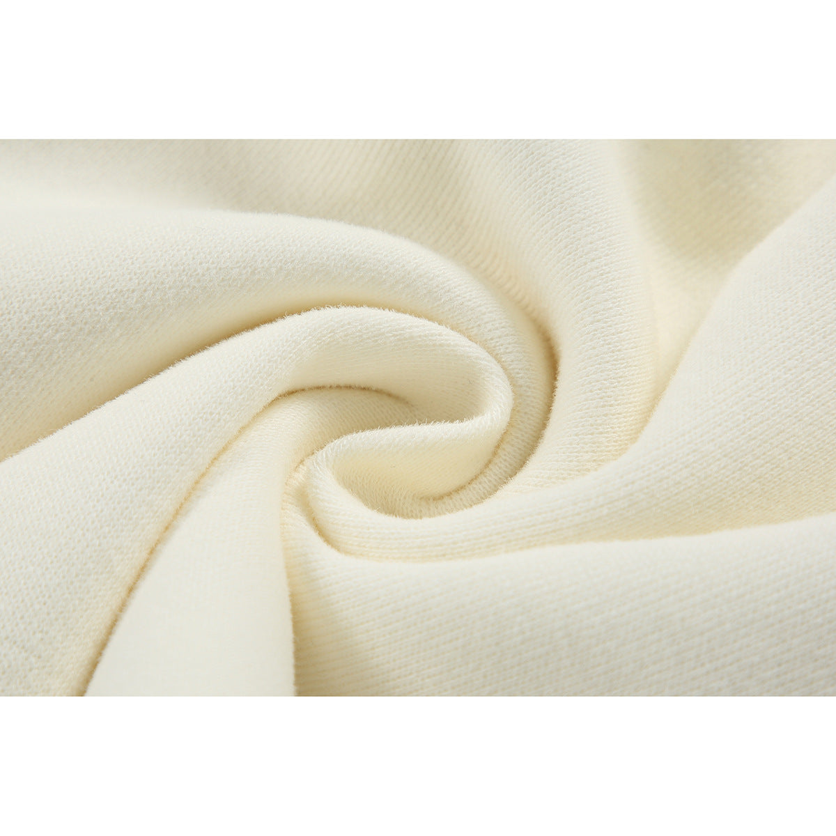 Macro view of ivory fabric folded into a swirl, showing its fine surface texture.