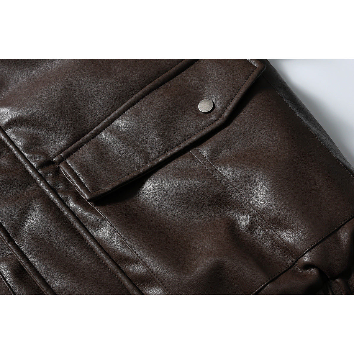 Close-up of a dark brown jacket's flap pocket with a metal snap and visible stitching.