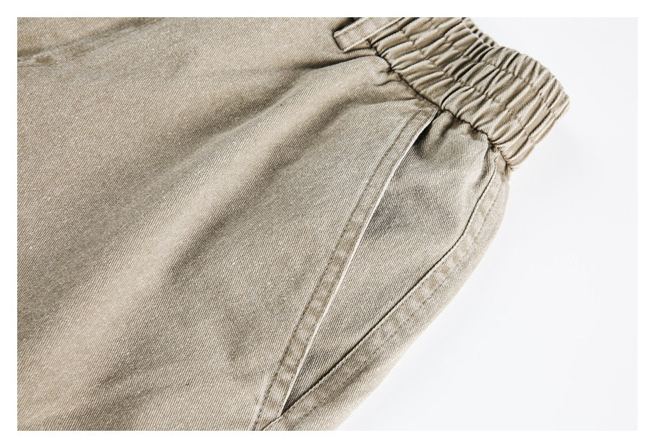 Close-up of beige pants showing the elastic waistband and angled front pocket.