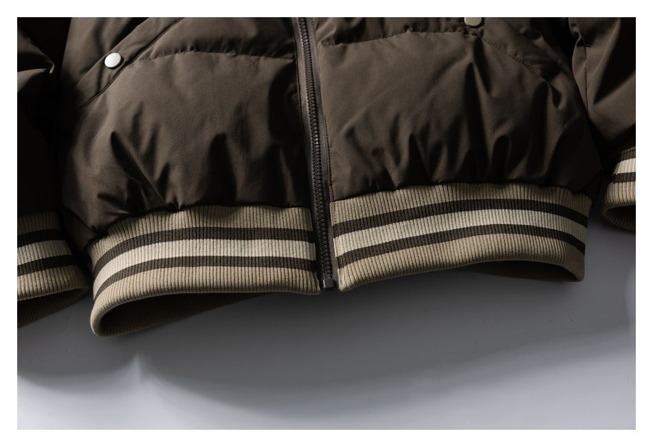 Close-up of a dark brown jacket's striped ribbed hem, center zipper, and snap-button pockets.