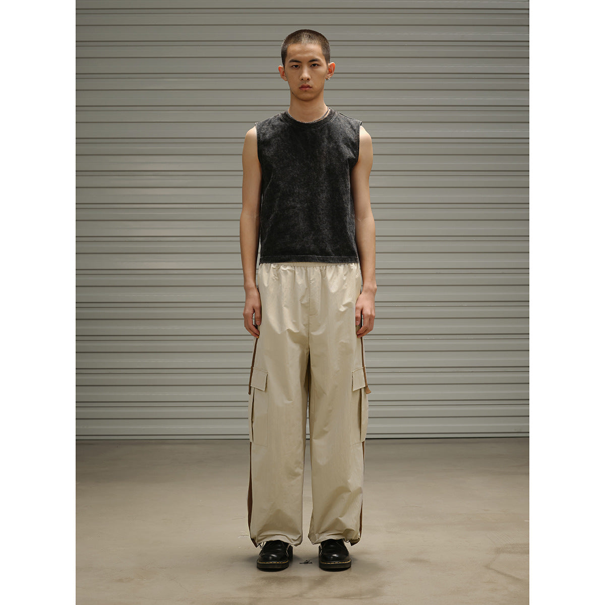 Front view of a model wearing a black sleeveless top and loose beige cargo pants with side pockets.