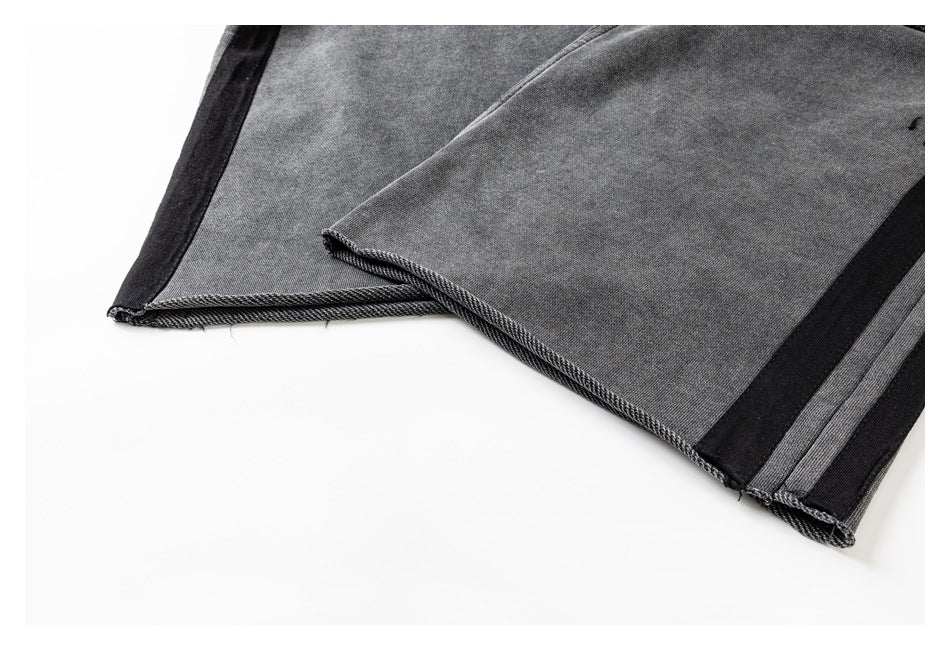 Close-up of charcoal gray garment hems with black side trim and visible stitching.
