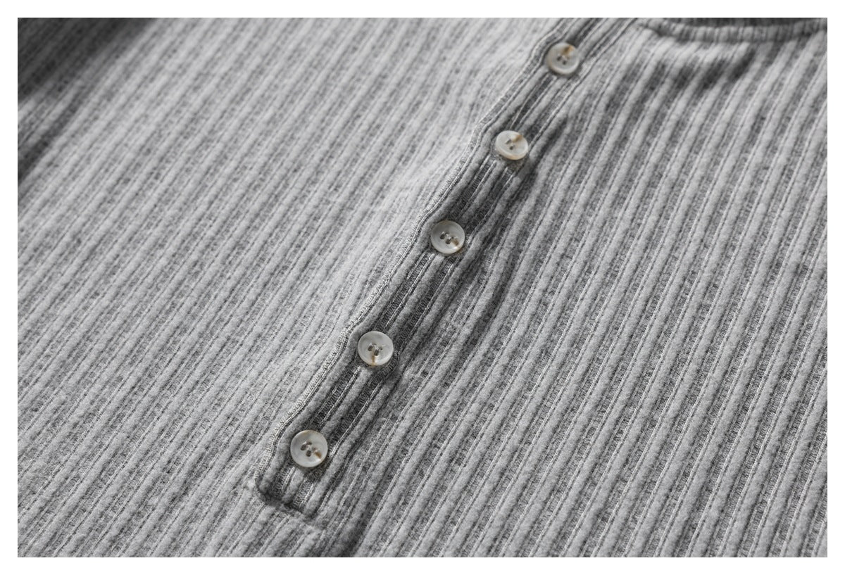 Close-up of a gray ribbed garment's button placket with five light-colored buttons.