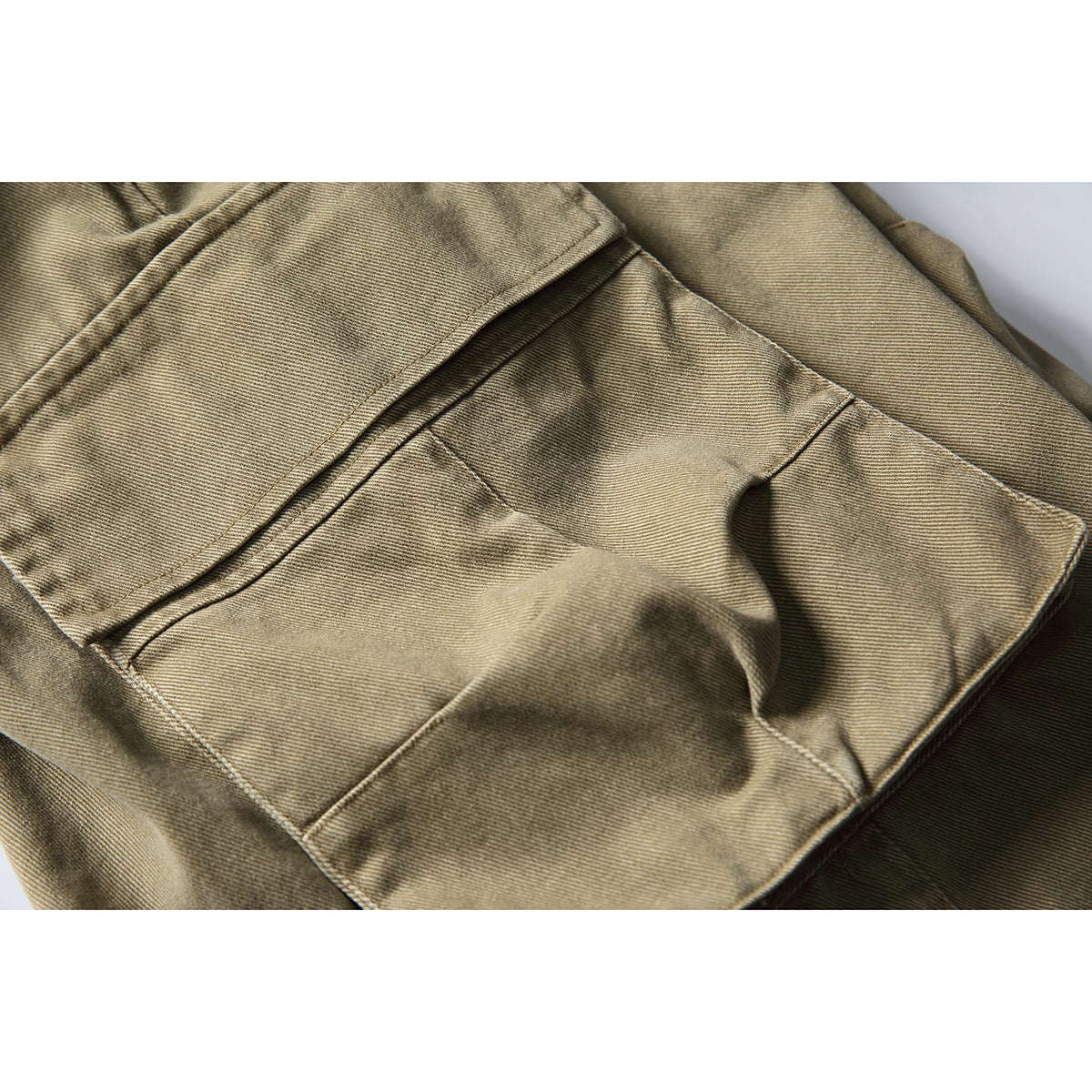 Close-up of a large stitched cargo pocket on khaki shorts.