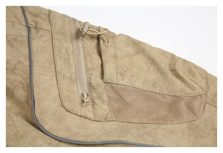 Close-up of tan trousers showing a zippered pocket, mesh panel, and adjustable cord.