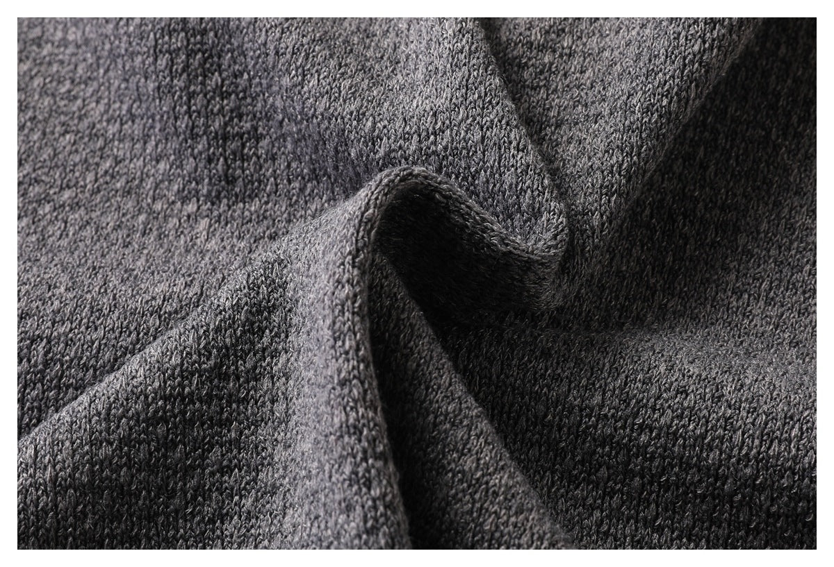 Close-up of gray knit fabric gathered into folds, showing its stitch texture.