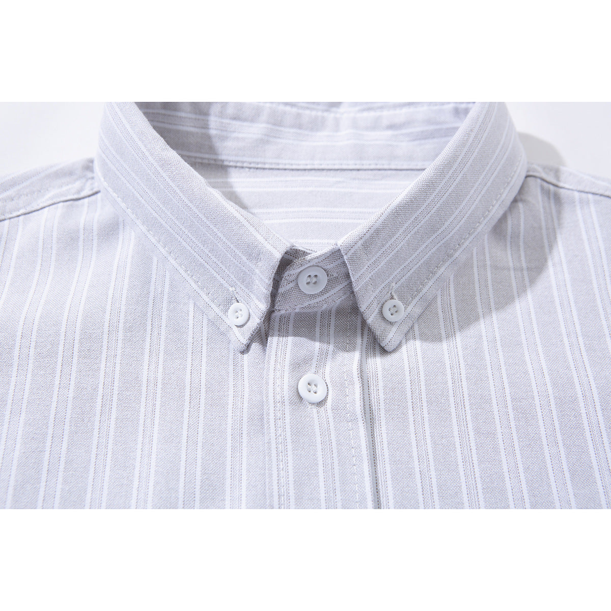 Close-up of a pale gray striped shirt's button-down collar and front buttons.