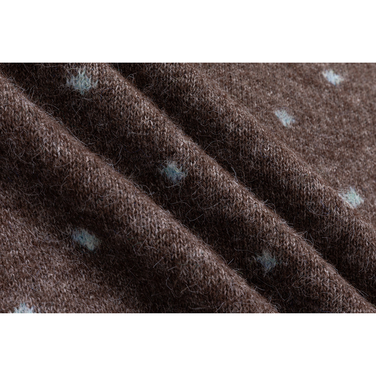 Macro view of fuzzy brown knit fabric with small pale blue dots.