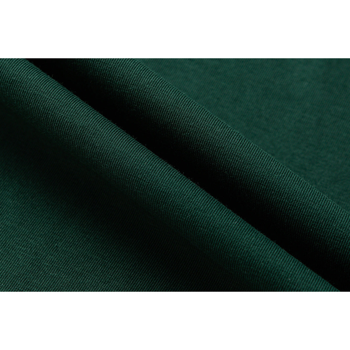 Macro view of dark green fabric folded to show its fine ribbed knit texture.